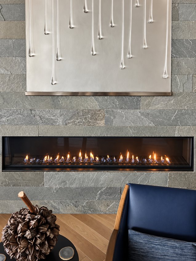 A wide linear fireplace set into a gray stone feature wall
